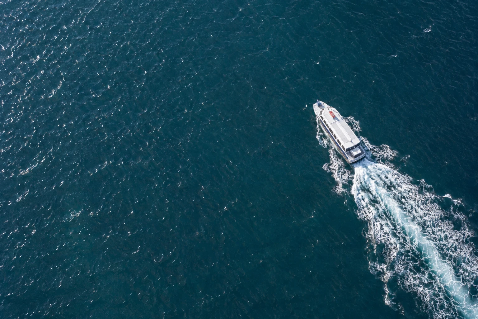 A ferry and its wake across blue-green water — conceptual brand imagery