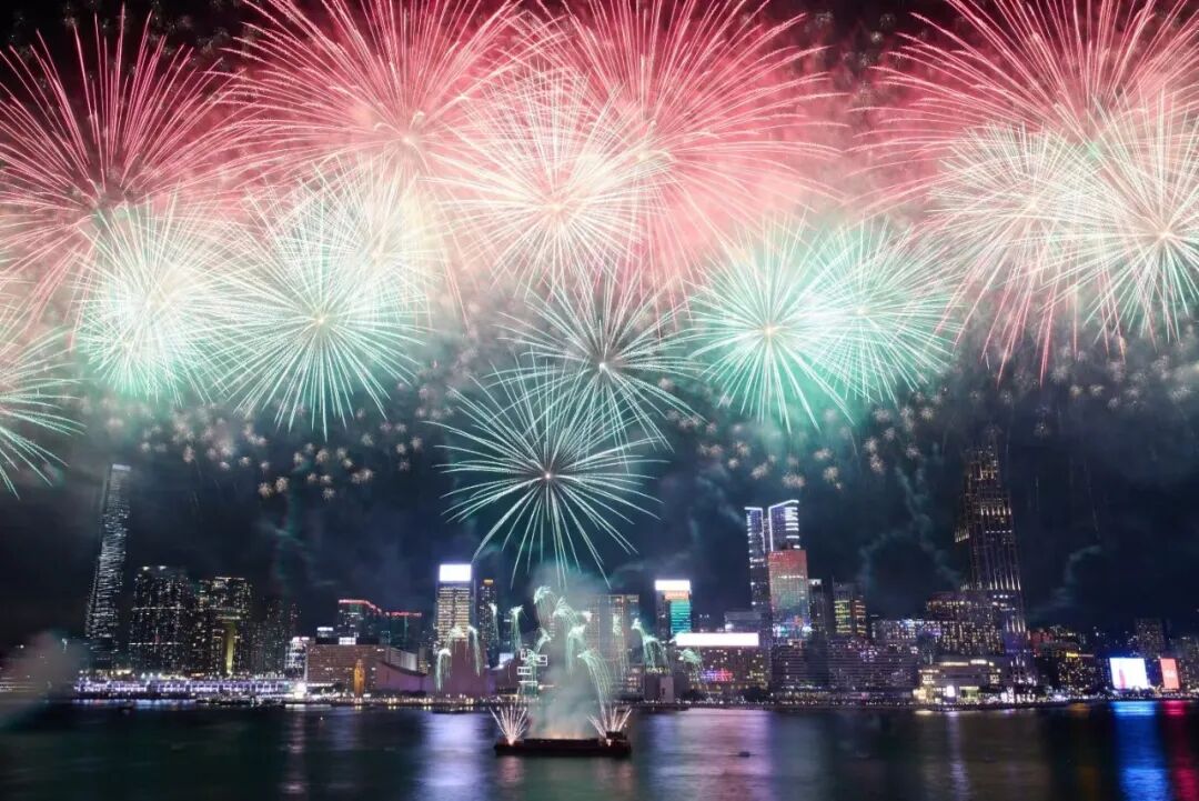 Multicoloured fireworks above the illuminated Victoria Harbour waterfront